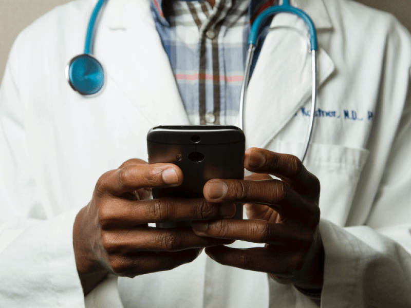 Doctor utilizing phone with emphasis on personal home care assistance.